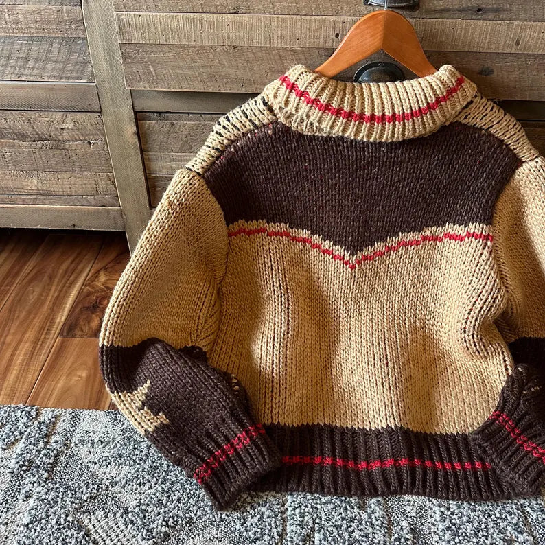 Knitted sweater with a pattern on a wooden hanger against a wooden wall.