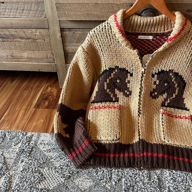 Knitted sweater with horse designs on a hanger against a wooden background
