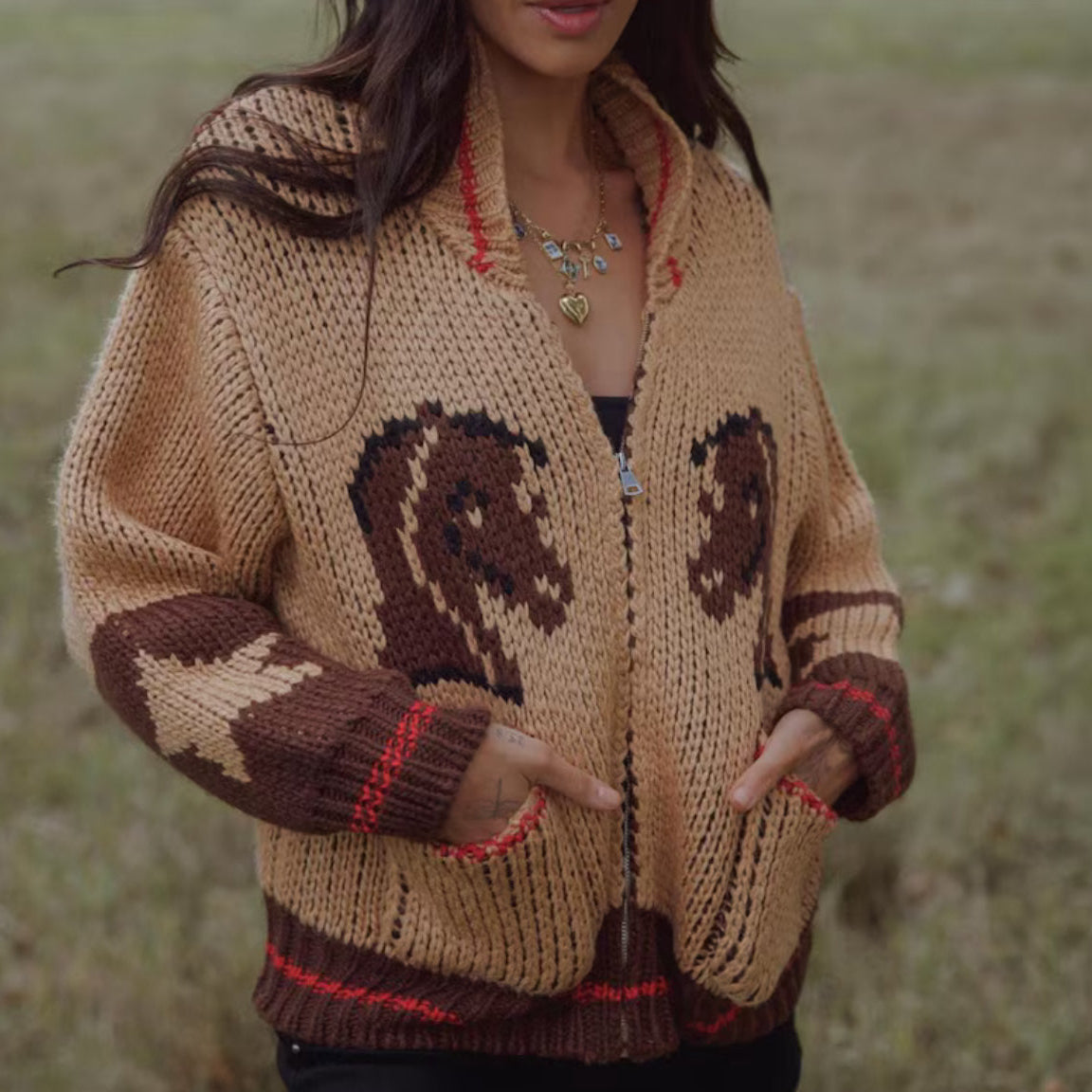 Person wearing a brown knitted cardigan with horse designs outdoors.