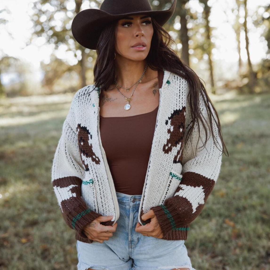 Woman wearing a patterned cardigan with animal designs outdoors.