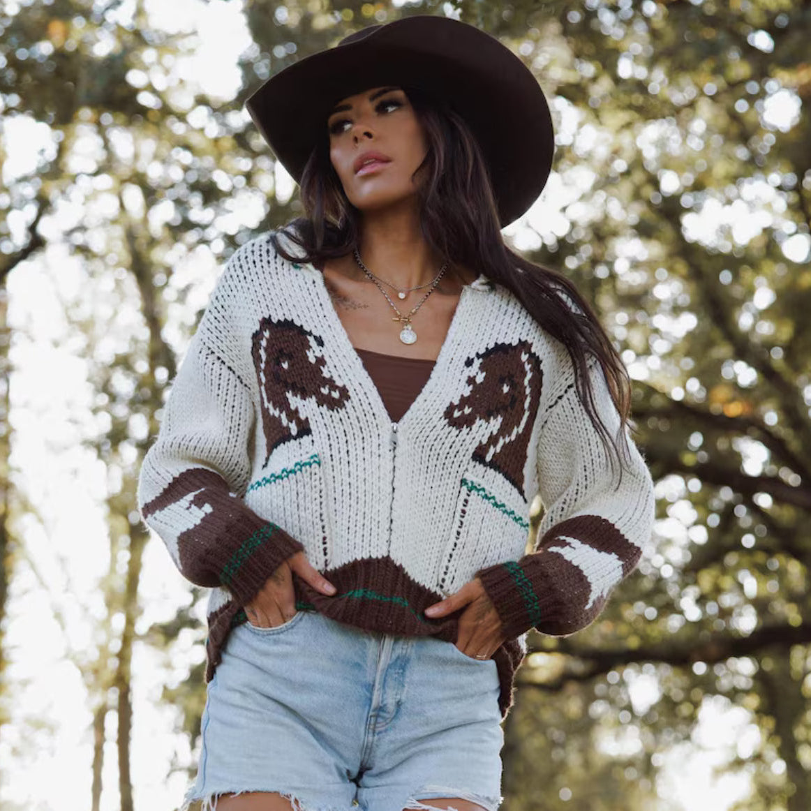Woman wearing a patterned sweater and hat in a forest setting