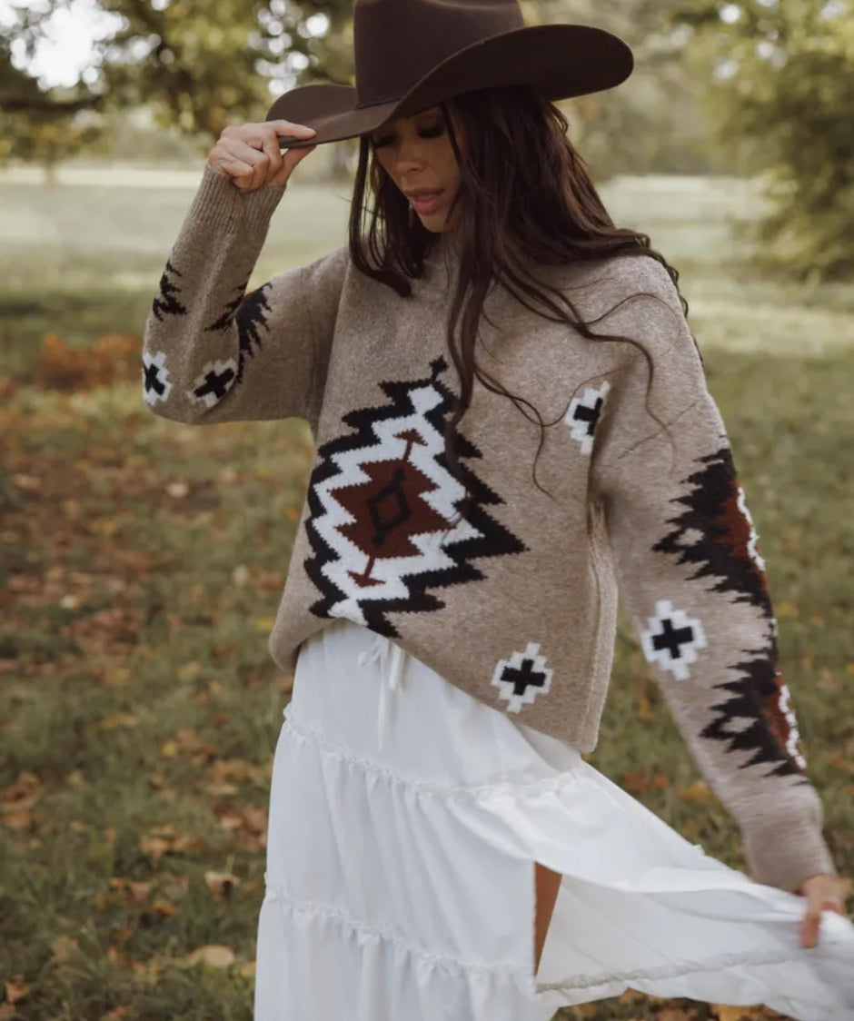 Woman wearing a patterned sweater and white skirt outdoors