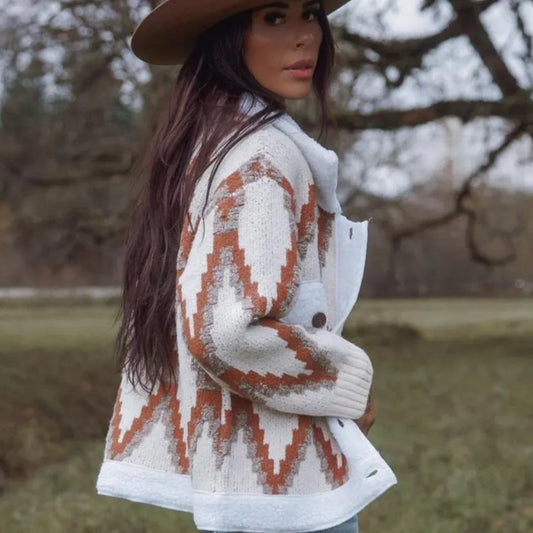 Woman wearing a patterned cardigan and hat outdoors