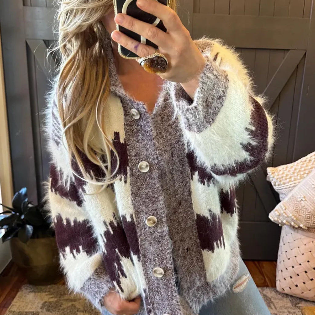 Person wearing a patterned cardigan taking a mirror selfie.