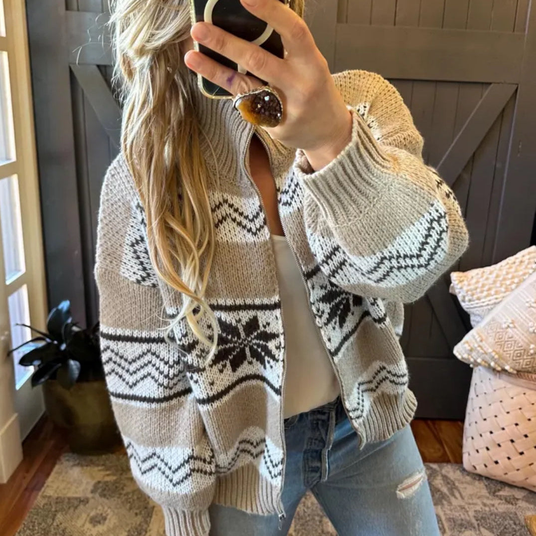 Person wearing a patterned sweater taking a mirror selfie indoors.