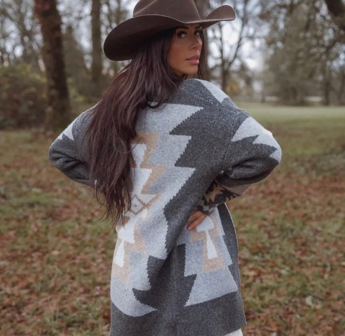 Woman wearing a patterned sweater and cowboy hat in an outdoor setting