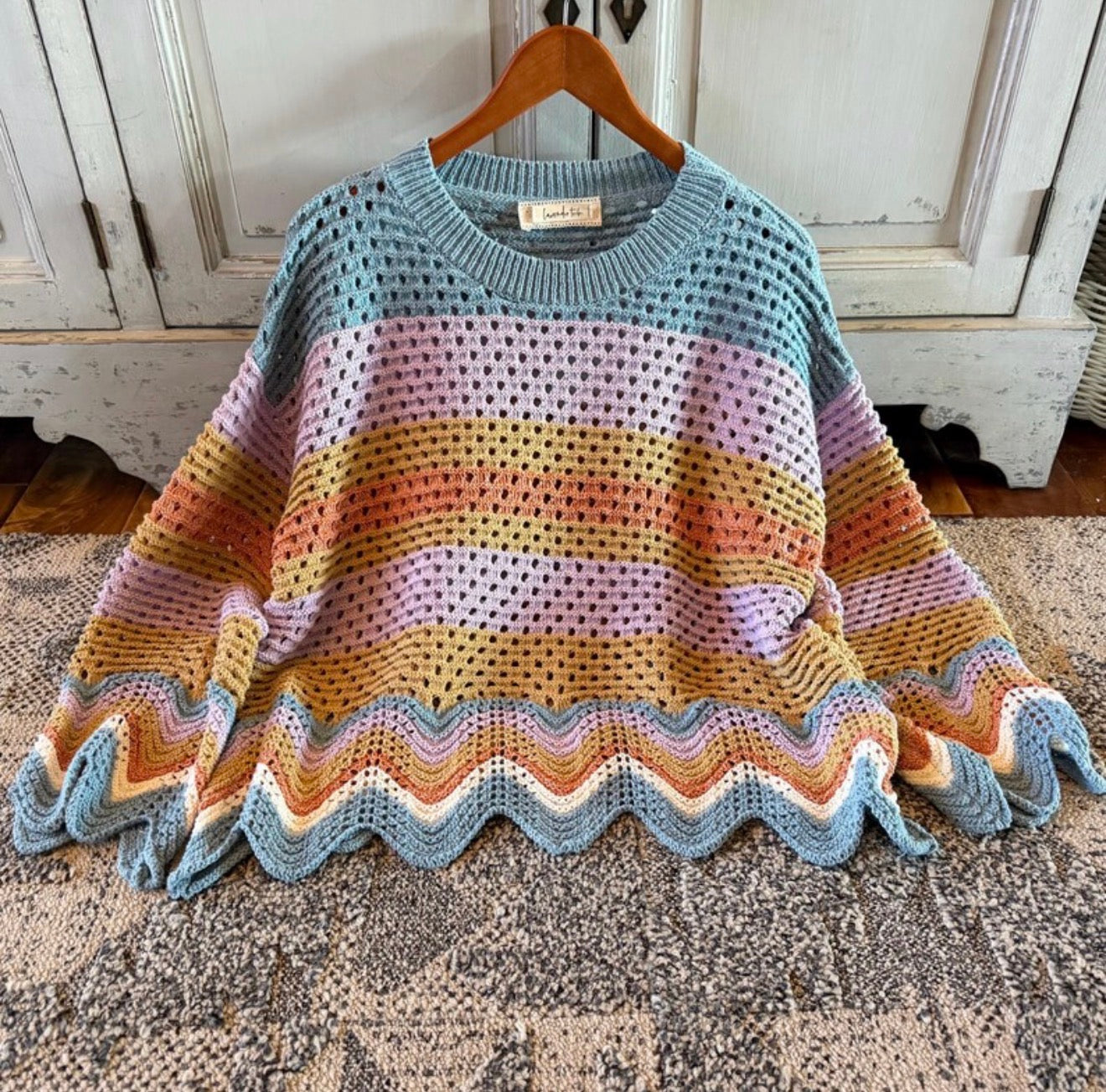 Colorful knitted sweater on a hanger with a wooden background