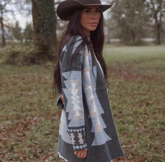 Woman wearing a patterned cardigan and cowboy hat in an outdoor setting