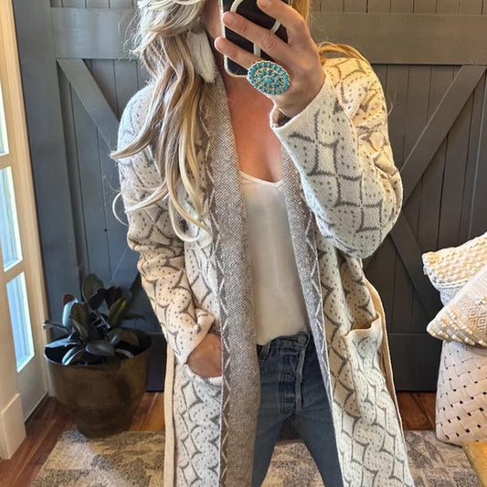 Blond Model The Henry Faire Isle Geometric Print Long Belted Cardigan Sweater by Lavender Tribe Design.&nbsp;Darling Western geometric argyle pattern on the softest cotton base.
+ Belted Front
+ Super Soft Cotton Blended Yarn
+ Cream base with Grey pattern