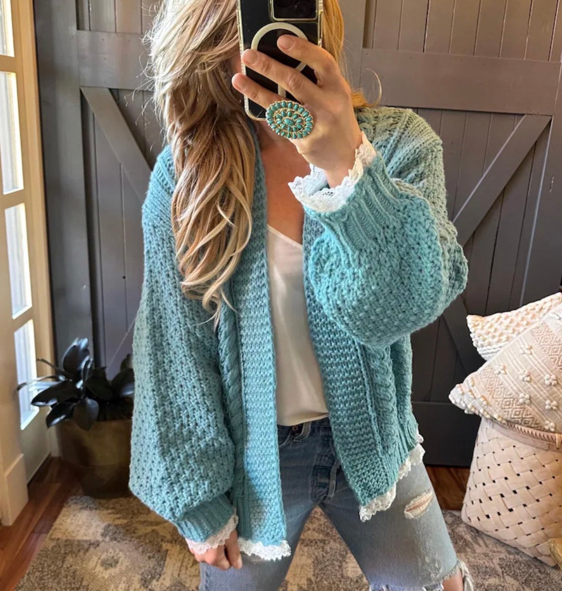 Person wearing a light blue knitted cardigan in a home setting