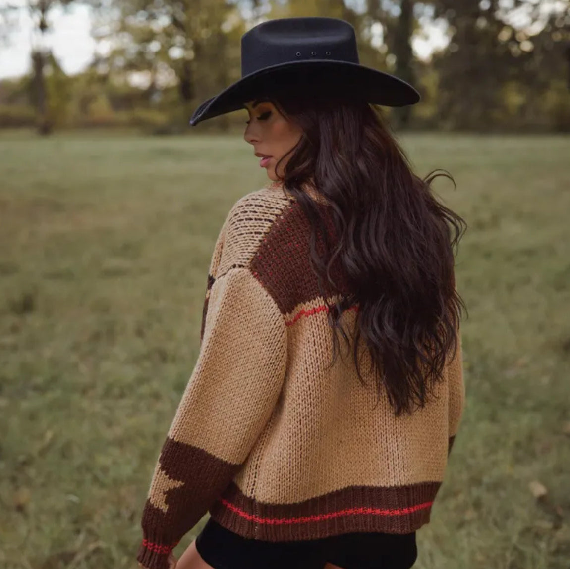 Woman wearing a patterned sweater and black hat in an outdoor setting