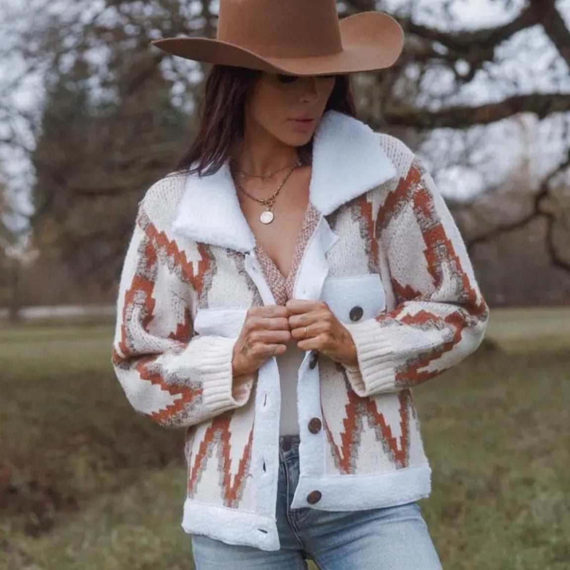 Woman wearing a patterned cardigan and brown hat outdoors