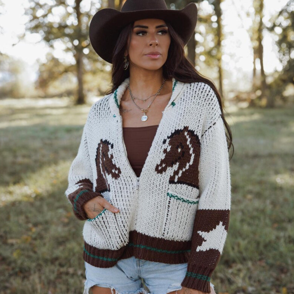 Woman wearing a patterned cardigan with horse designs outdoors.