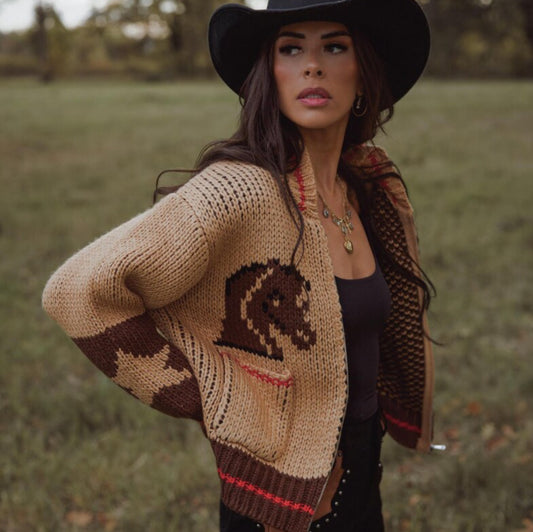 Woman wearing a patterned cardigan with a horse design in a field