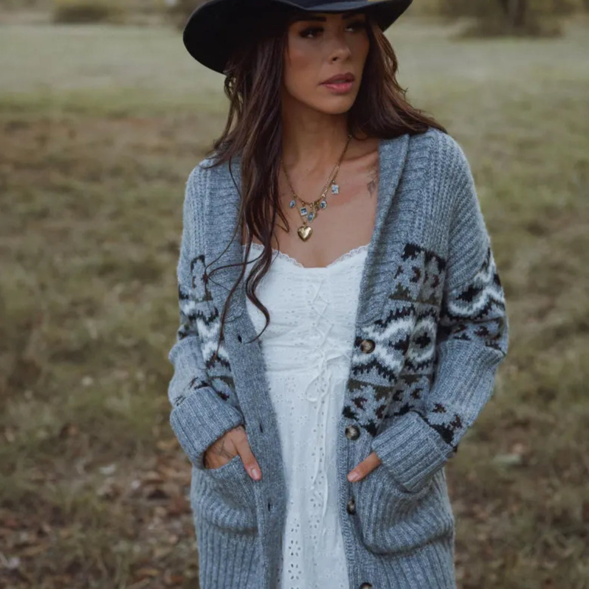 Woman wearing a long gray cardigan with a pattern in an outdoor setting
