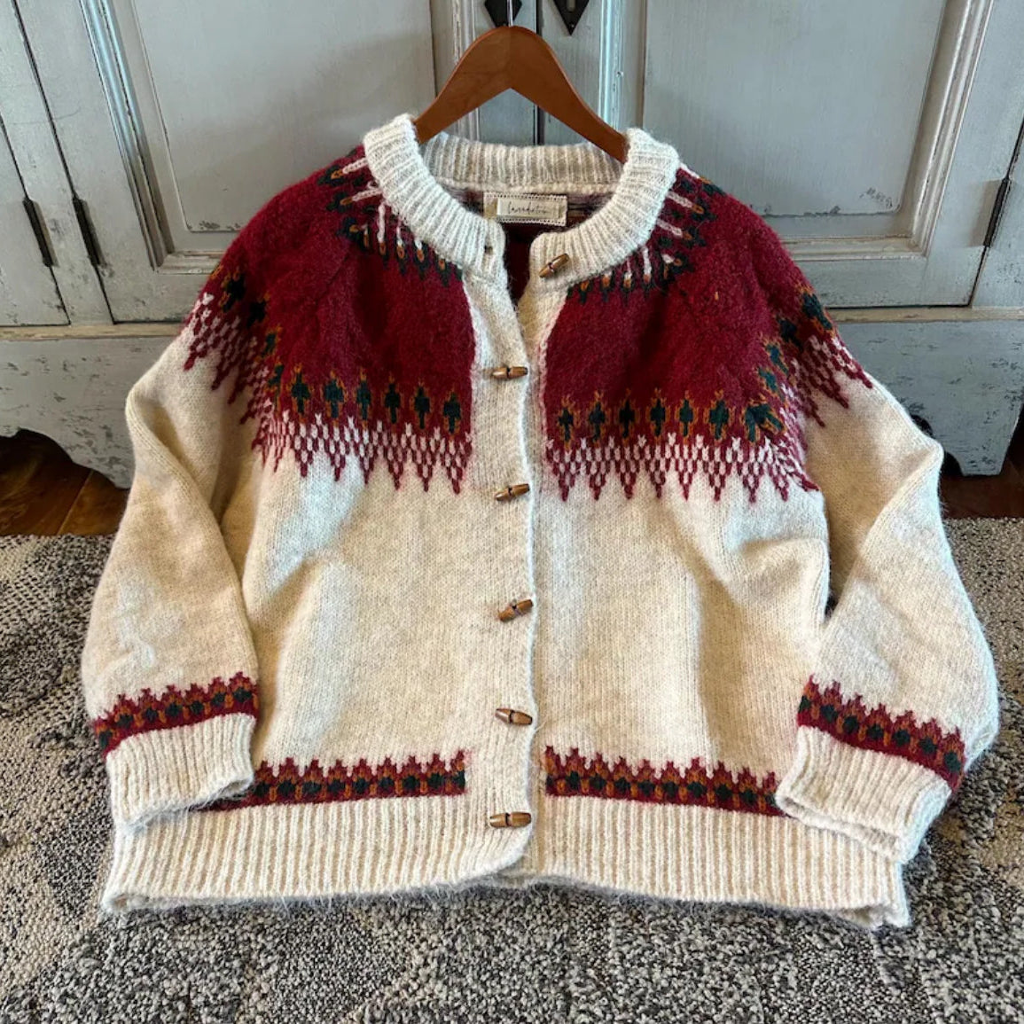 Knitted cardigan with red and black patterns on a hanger