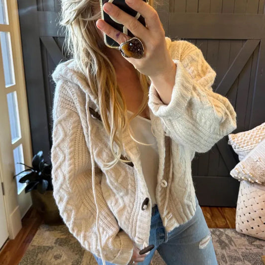 Person wearing a beige knitted cardigan in a home setting