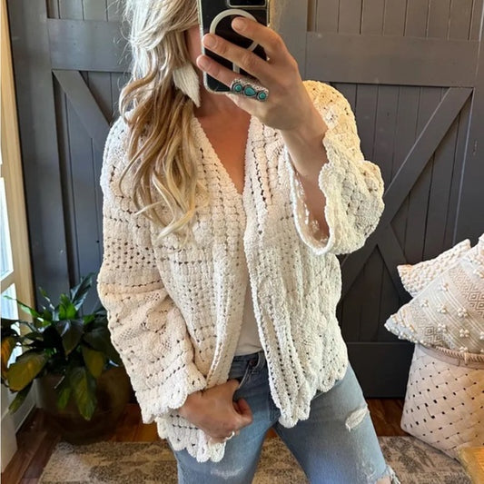 Person wearing a white crochet cardigan in a home setting