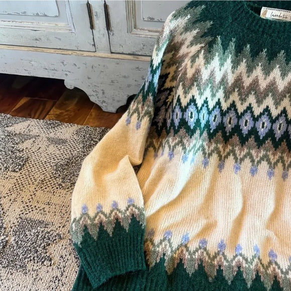 Knitted sweater with a pattern draped over a chair in a room.